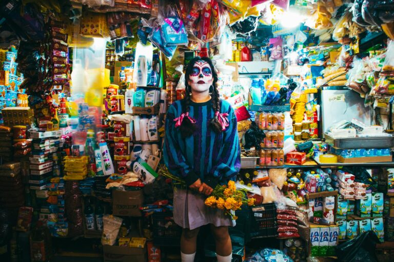 Vibrant Day of the Dead Catrina makeup inside a bustling Chiapas market, surrounded by goods.