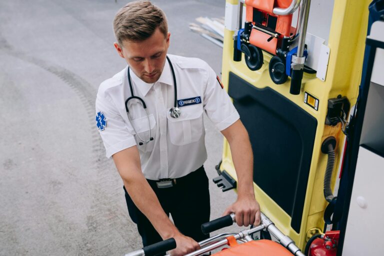 A paramedic prepares a stretcher for use outside an ambulance, showcasing healthcare urgency.